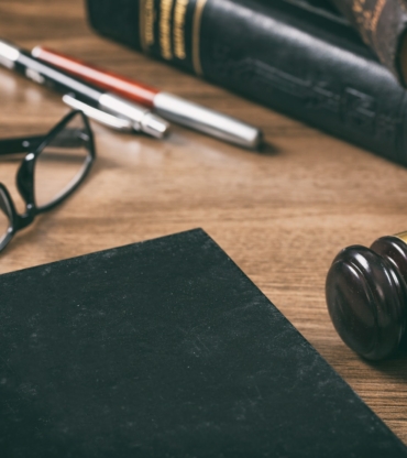 Law or auction gavel and a book, wooden office desk background. Closeup view, space for text